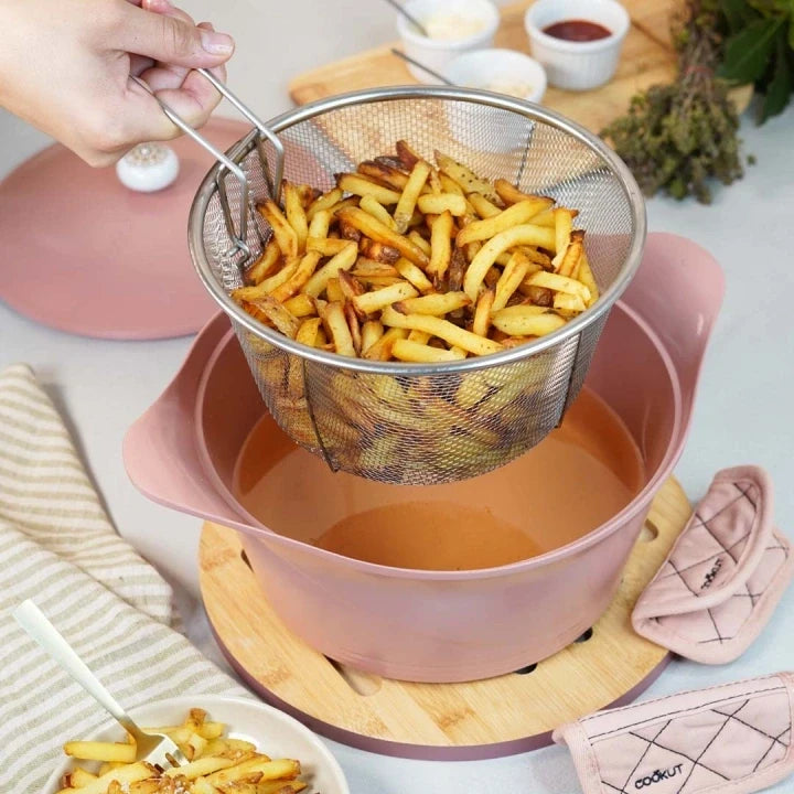 Panier de friture en acier inoxydable Cookut de 28 cm rempli de frites maison au-dessus d'une cocotte rose