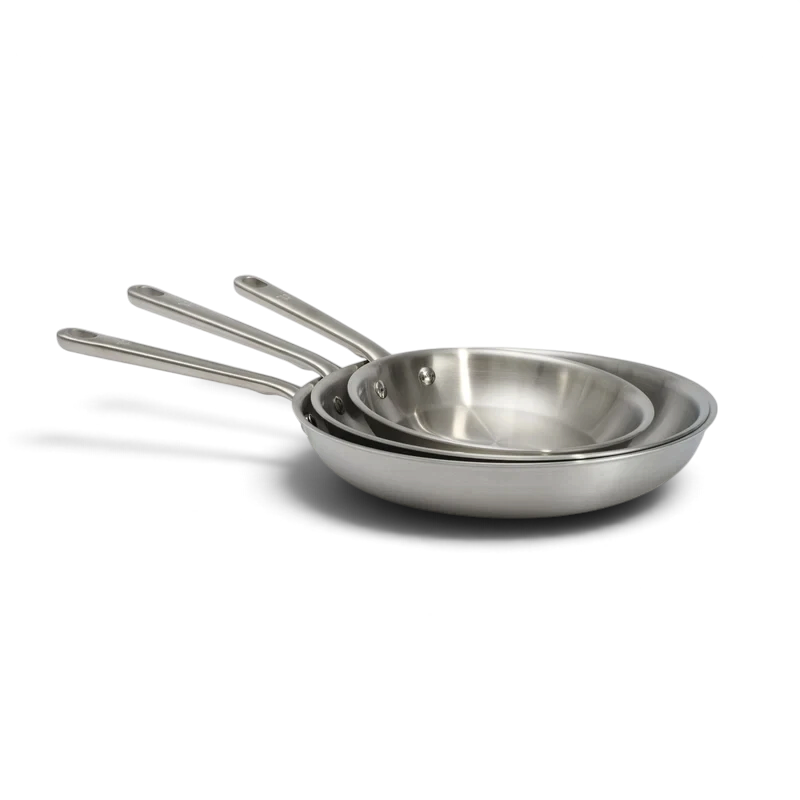 Set de 3 poêles en inox Atma chez Du Bruit dans la Cuisine, empilées pour montrer leur finition acier inoxydable
